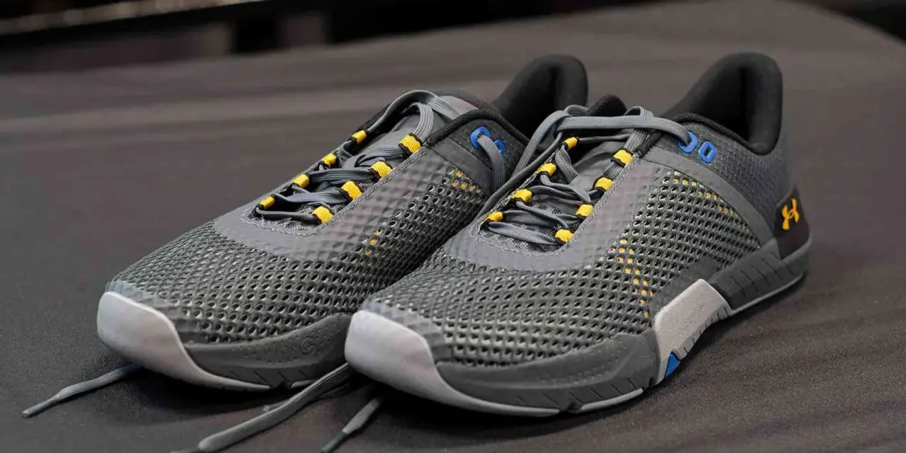 Szare buty sportowe z żółtymi akcentami, idealne jako buty do crossfitu. Solidna konstrukcja i przewiewna siateczka zapewniają komfort.