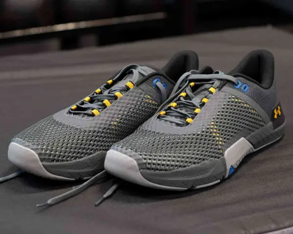 Szare buty sportowe z żółtymi akcentami, idealne jako buty do crossfitu. Solidna konstrukcja i przewiewna siateczka zapewniają komfort.