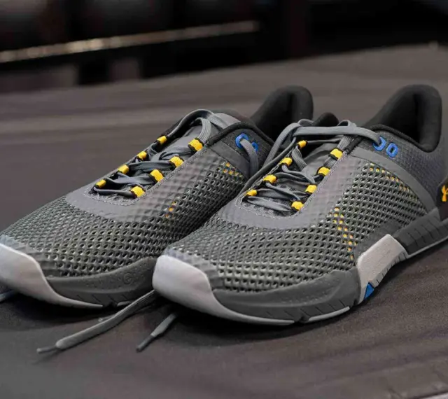 Szare buty sportowe z żółtymi akcentami, idealne jako buty do crossfitu. Solidna konstrukcja i przewiewna siateczka zapewniają komfort.