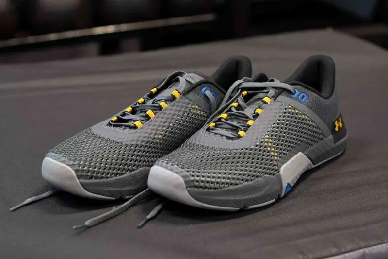 Szare buty sportowe z żółtymi akcentami, idealne jako buty do crossfitu. Solidna konstrukcja i przewiewna siateczka zapewniają komfort.